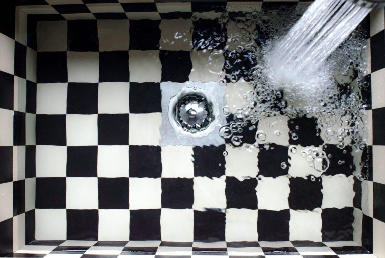 Agua cayendo por el desagüe de un fregadero, símbolo de tuberías sin atascos