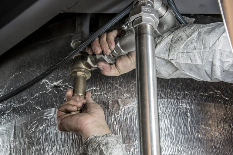 Fontanero detectando una fuga de agua bajo el fregadero de la cocina en una vivienda de Valencia