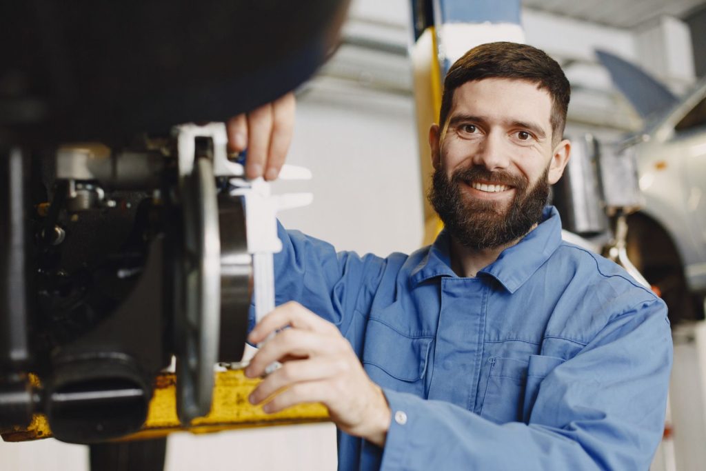 Fontanero profesional sonriente con camisa de trabajo azul durante una reparación en Valencia