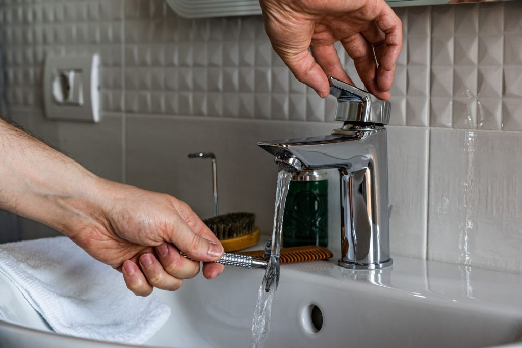Fontanero instalando un grifo monomando moderno en el lavabo de un baño