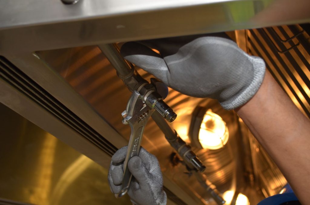 Fontanero profesional trabajando con una llave inglesa bajo un fregadero durante una reparación en Valencia